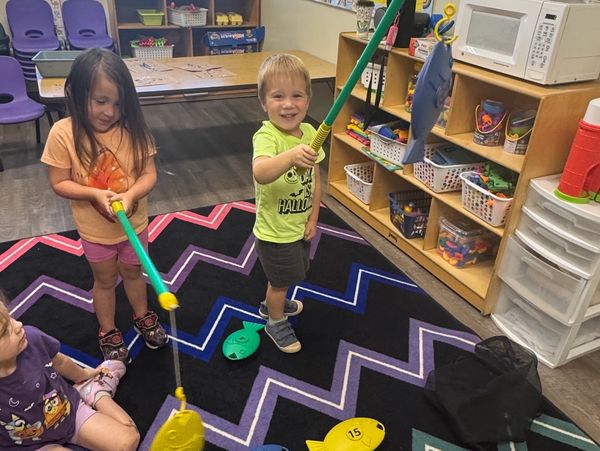 Children playing fishing game indoors.