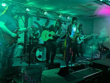 A band performs live on stage with colorful lighting and fog effects.