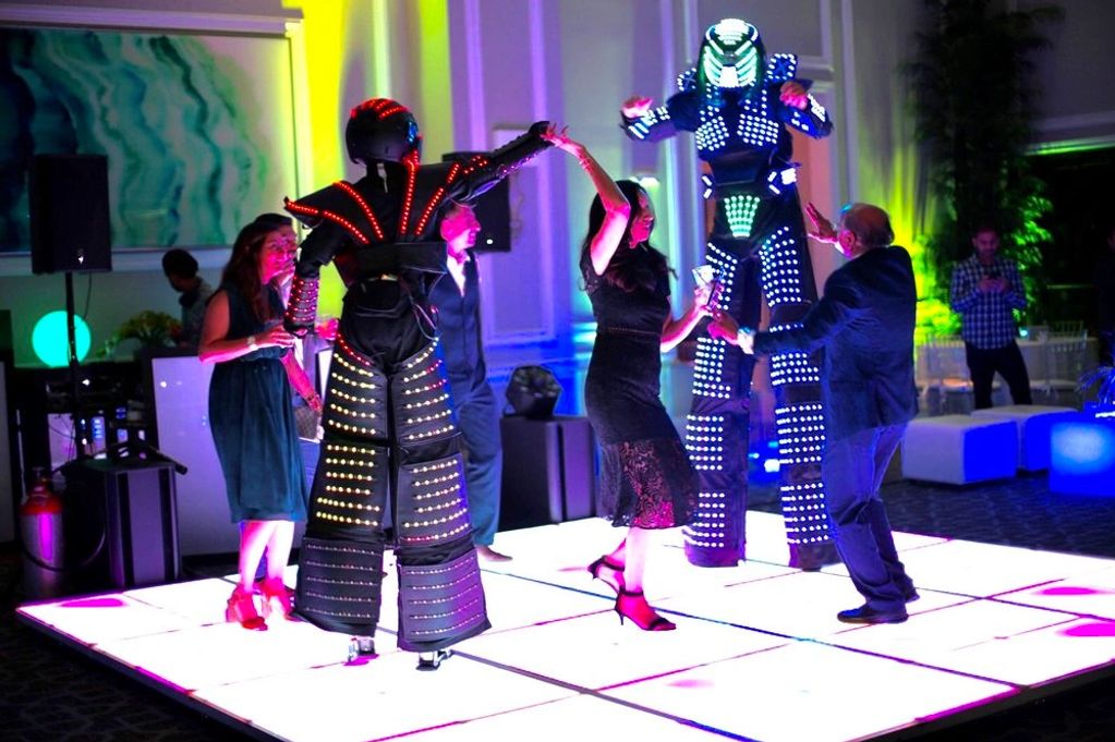 LED robots dancing with guests on the LEd dance floor at a party. 