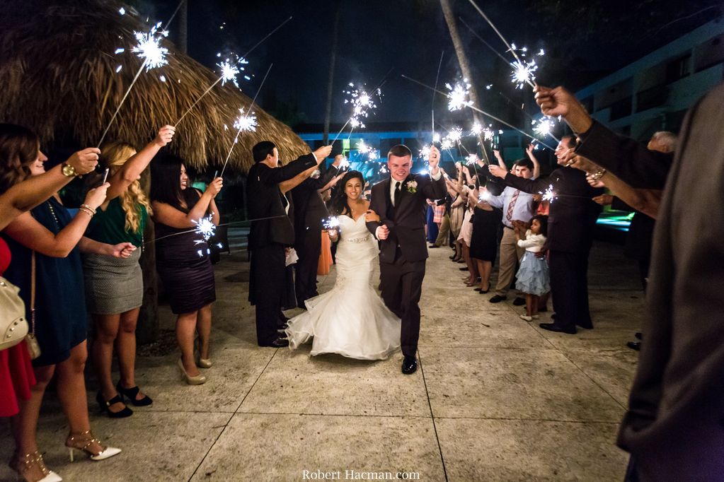 Bride and groom walking under guests with firework sparklers. 