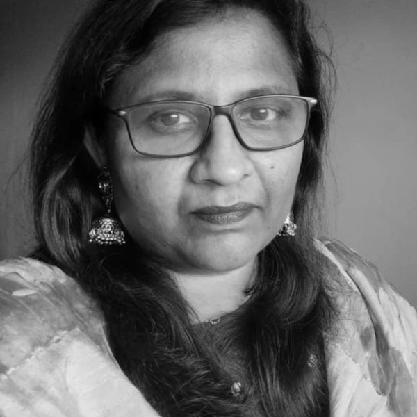 A woman with glasses wearing traditional earrings and attire.