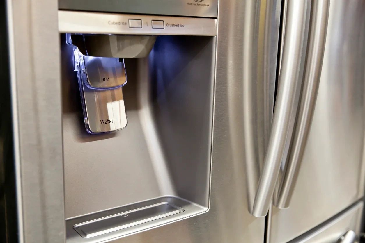 A chrome colored refrigerator in top shape featuring a water a dispenser.
