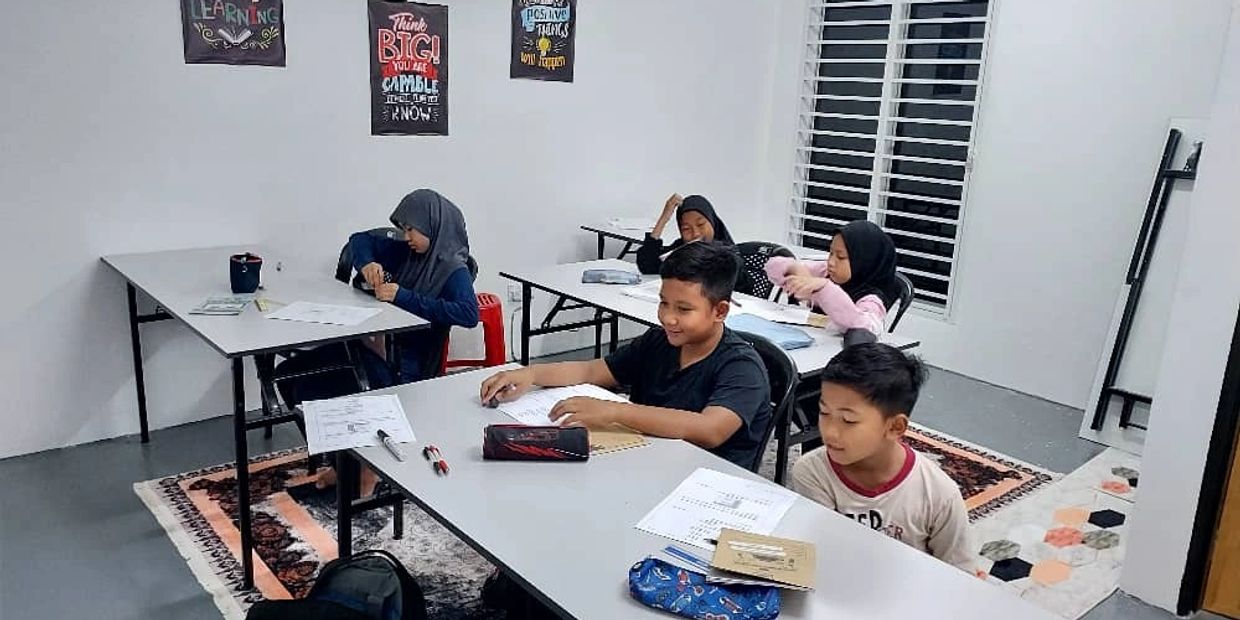 Children studying together in a bright classroom with educational posters.