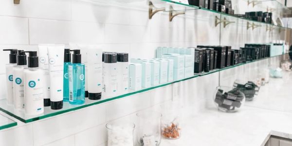 Skincare products neatly arranged on a glass shelf.