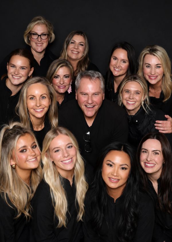 Group of smiling people posing together against a black background.
