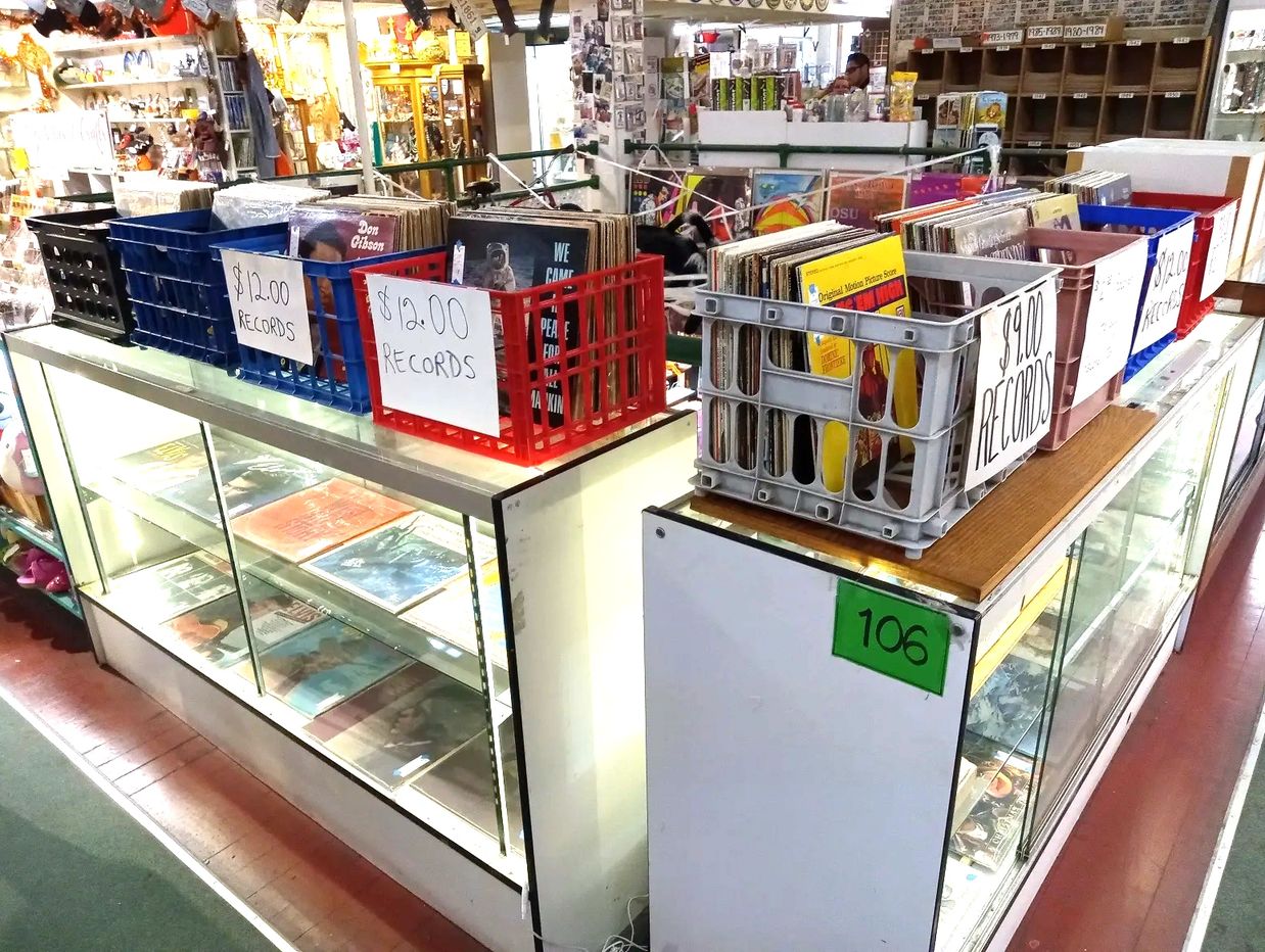 2 display cases with crates of vintage records on top.