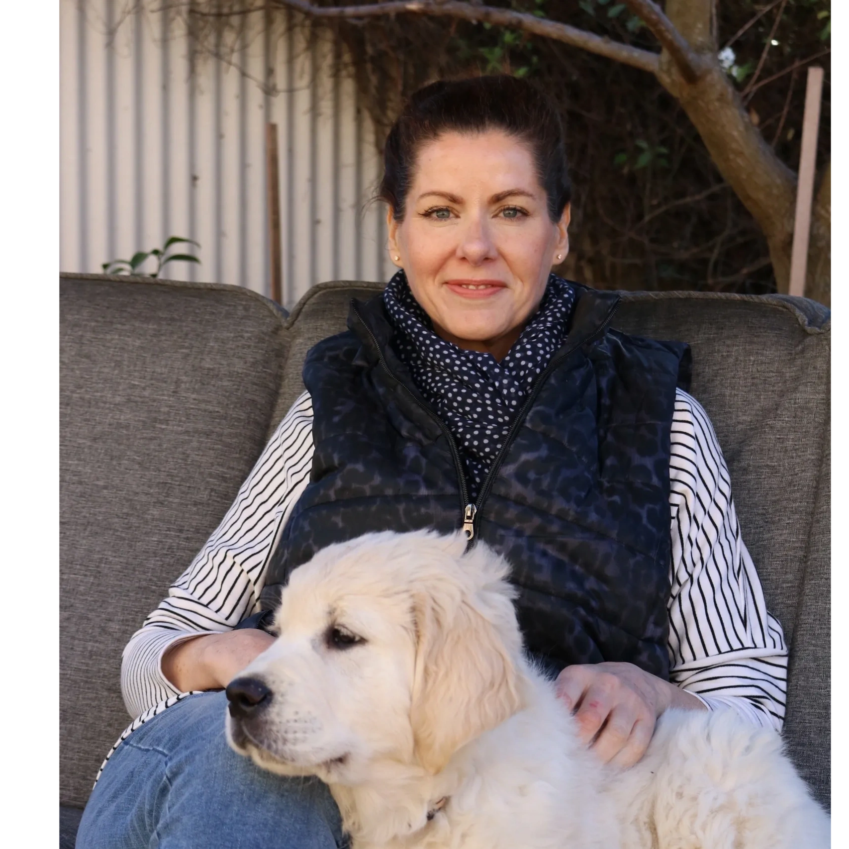 Jen Thomas sitting in the garden with Bailey, one of her golden retrievers.
