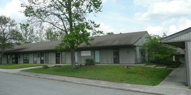 Single-story office building with a tree and grassy lawn.