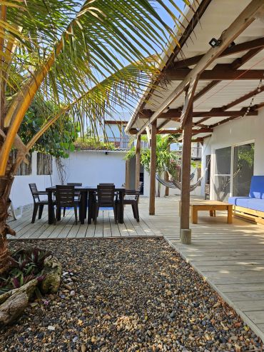 Terrasse extérieure avec mobilier en bois et hamac.
