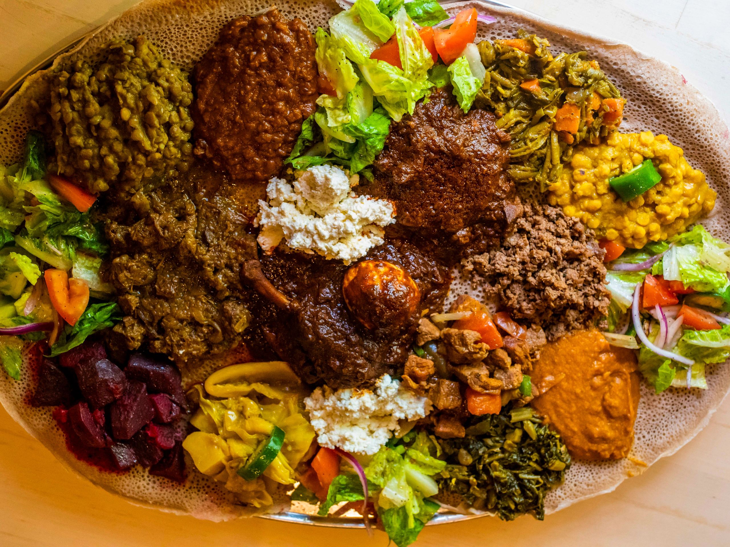 A colorful Ethiopian platter with various stews and vegetables on injera bread.