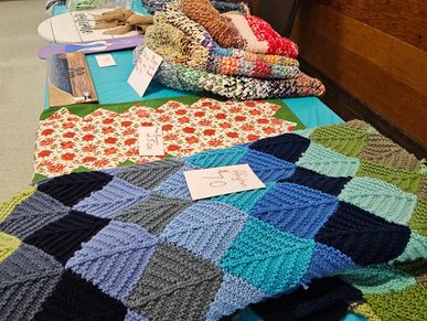 Handmade knitted and crocheted blankets displayed on a table.