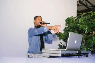 DJ performing with a microphone and laptop.