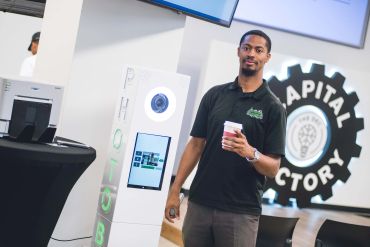 Man holding coffee in a tech space.