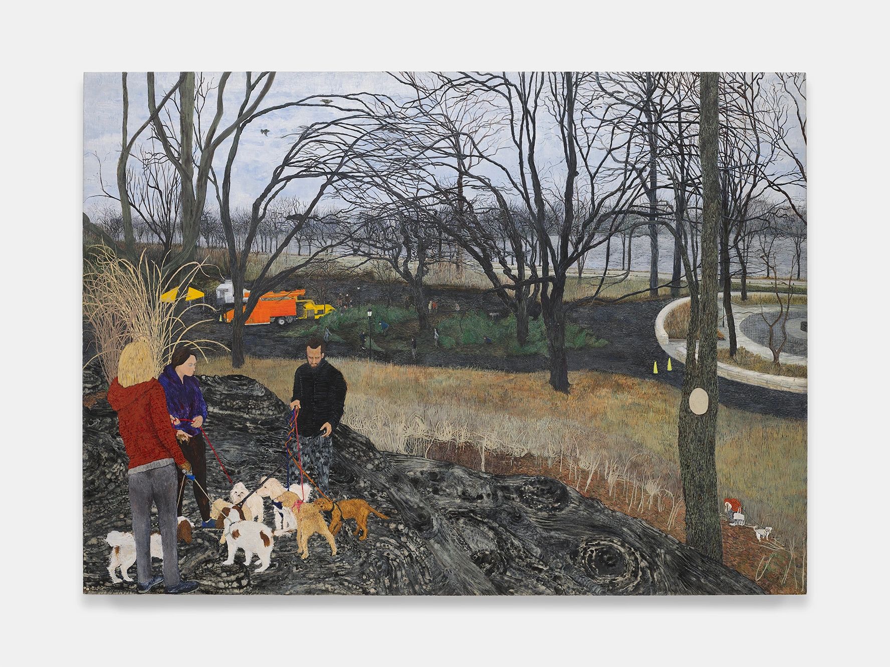 Three people walking multiple dogs in a park with leafless trees and a gray sky.