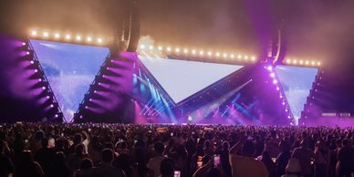 Large crowd enjoying a vibrant concert with colorful stage lights.