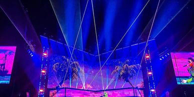 Concert stage with vibrant blue lights and palm tree visuals.