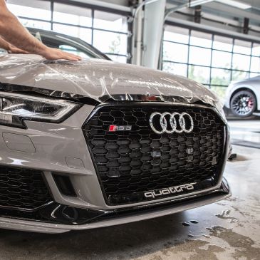 Close-up of an Audi S5 front grille with protective film being applied.