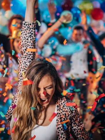 people at a party with balloons and streamers falling around them. 