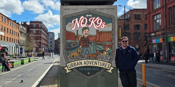 Man stands next to an urban dog adventure sign in a city setting.