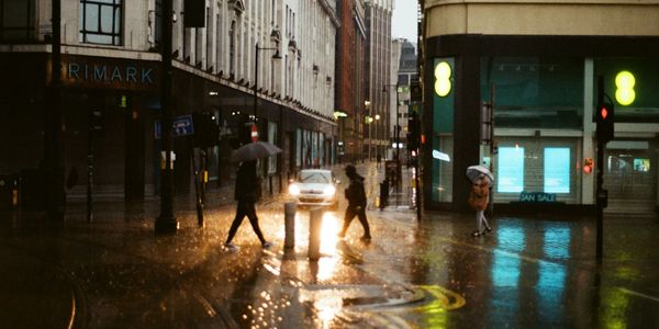 People with umbrellas crossing a rainy city street at night.