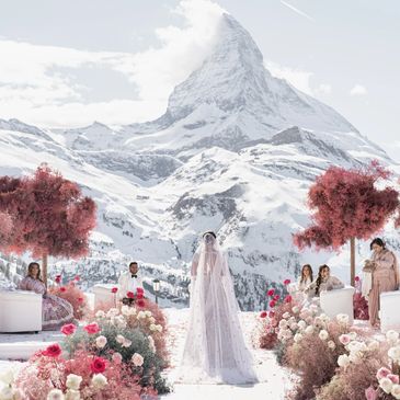 Bride standing with guests in snowy mountain wedding setup.