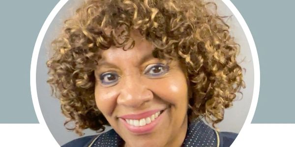 Close-up portrait of a smiling woman with curly hair.