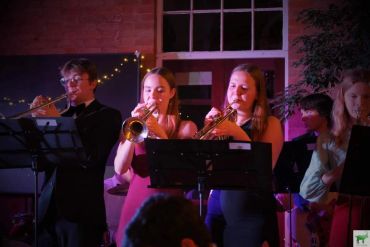 Three musicians playing brass instruments during a performance.