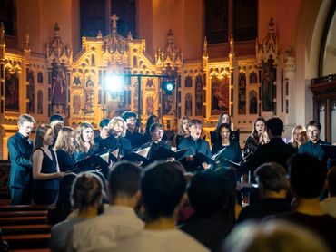 Choir singing in a beautifully lit church interior with attentive audience.