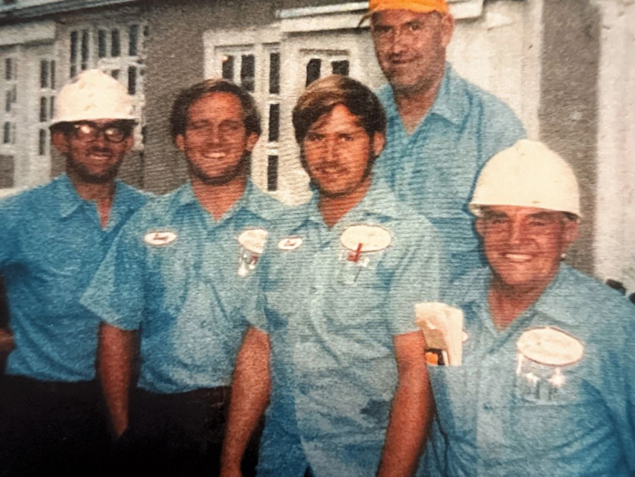 Group of five workers in blue uniforms and helmets.