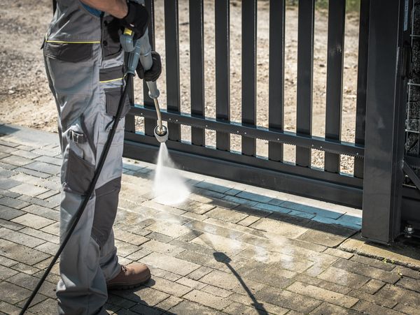 A professional washing the driveway with a  pressure washer