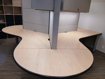 Empty office cubicles with wooden desks.