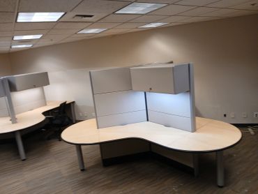 Empty office cubicles with desks and chairs.