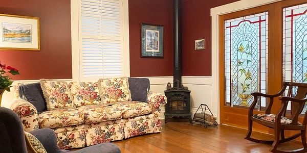 Parlor sitting room with sofa, gas fireplace, armchairs, and stained glass doors.