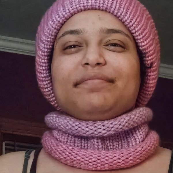 Person wearing a pink knitted hat and matching scarf.