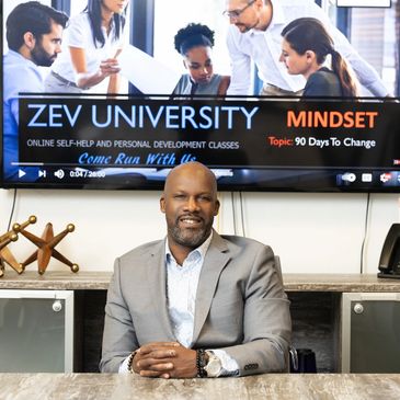 C.W. Zev sitting with a TV behind him