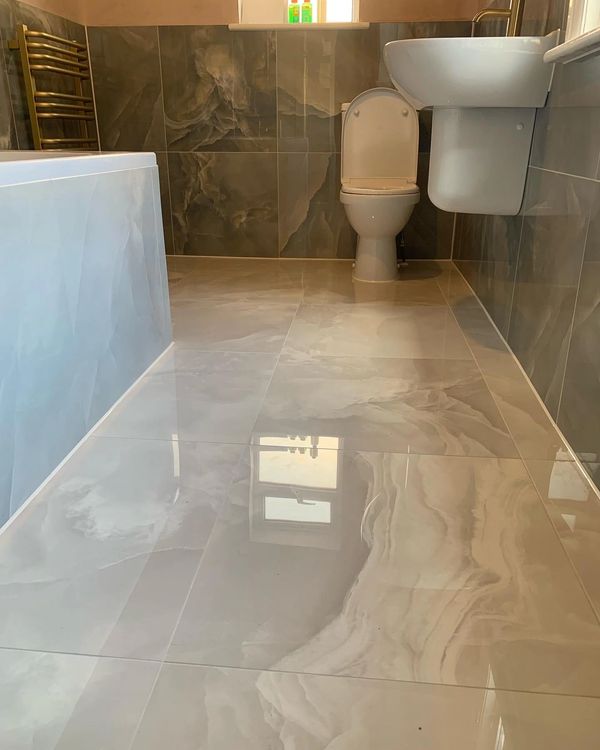 Modern bathroom with glossy marble tiles on floor and walls.