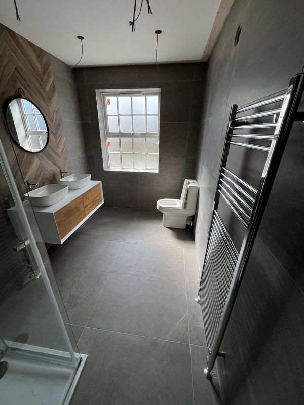 Modern bathroom with dual sinks, toilet, and heated towel rail.