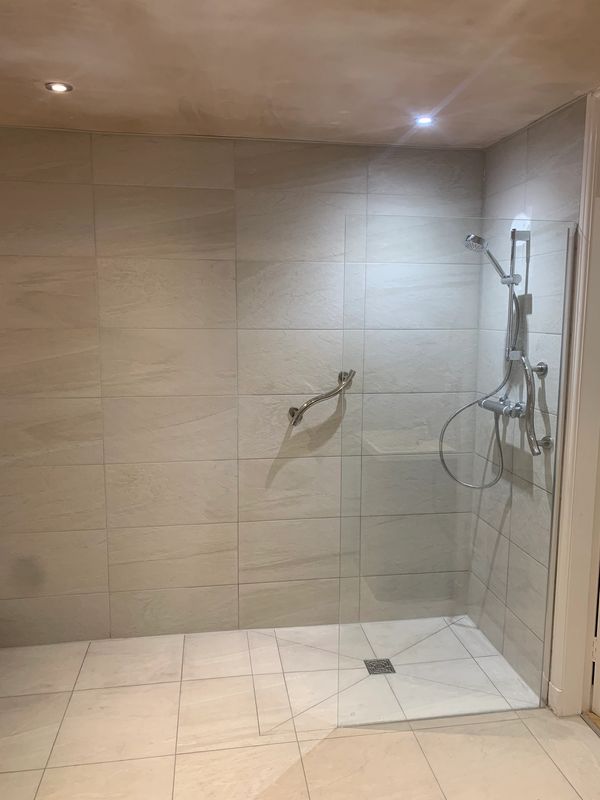 Minimalist walk-in shower with glass partition and chrome fixtures.