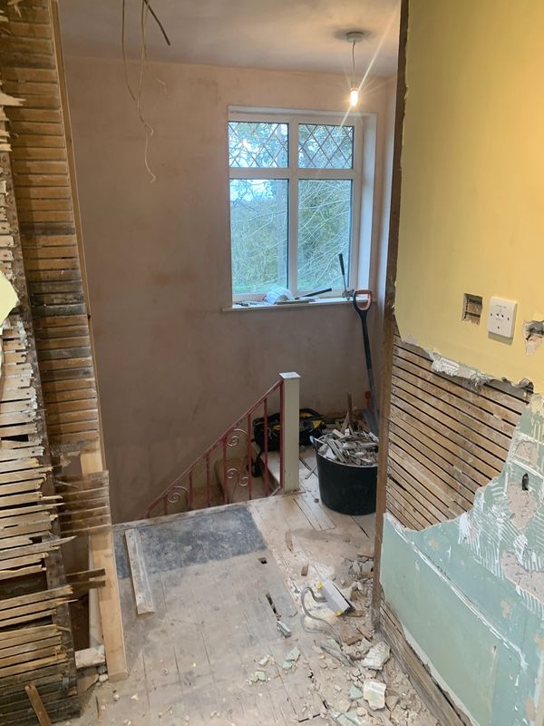 Indoor staircase area under renovation with debris and tools scattered.