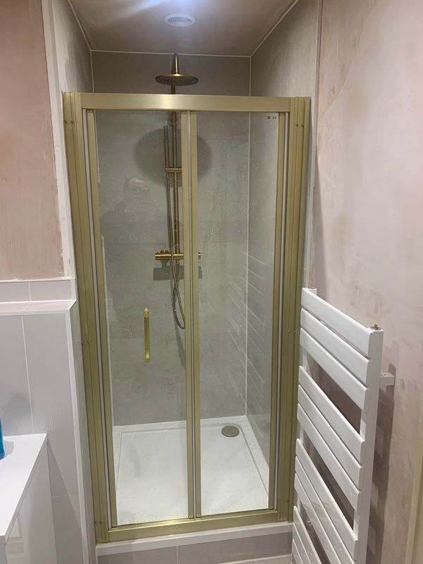 Modern shower enclosure with gold frame and rain showerhead.
