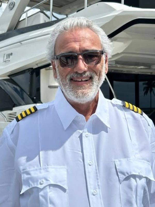 Smiling man in a captain's uniform with sunglasses.