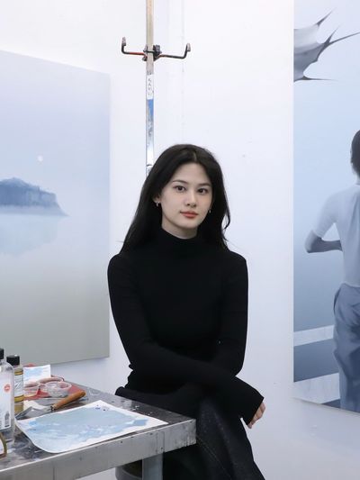 Young woman in black sitting in an art studio.