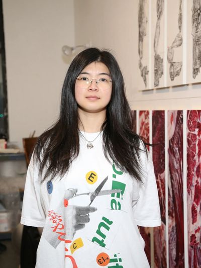 Young woman with long hair and glasses wearing a graphic T-shirt in an art gallery.