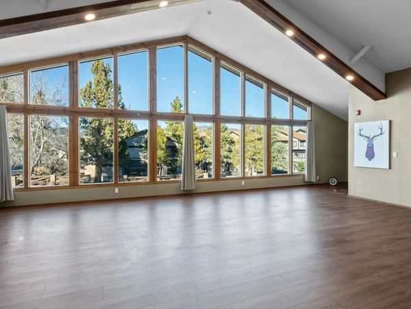 Spacious empty room with large windows and wooden flooring.