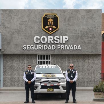 Dos guardias de seguridad frente a una camioneta y un edificio de seguridad privada.