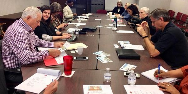 A group of adult leaders meet in a conference room setting.