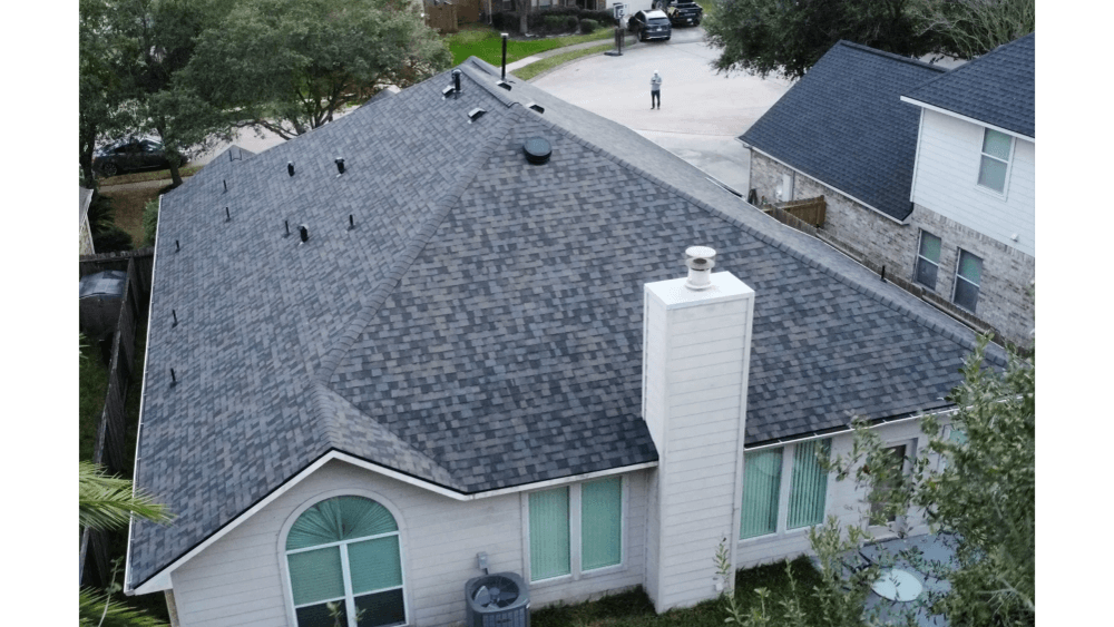 Finished dark shingle roof with brick chimney seen from above