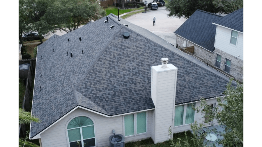 Finished dark shingle roof with brick chimney seen from above