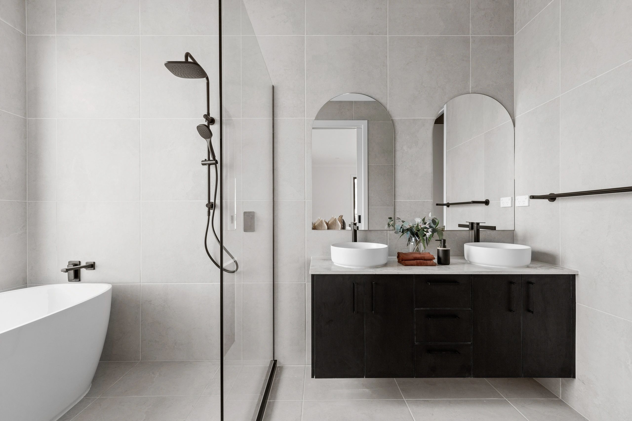 Modern bathroom with dual sinks, glass shower, and bathtub.