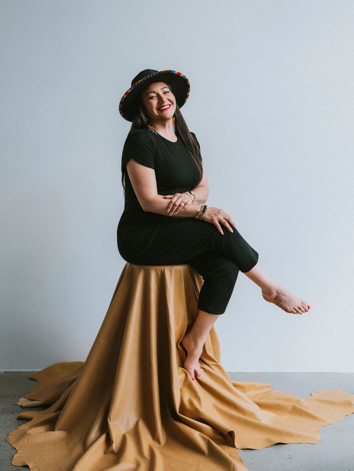 Woman in black outfit smiling while sitting on a draped table.